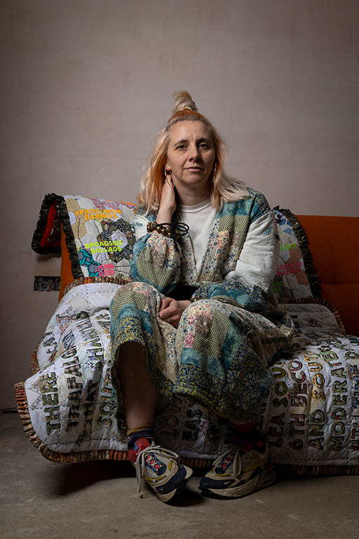 Blonde woman sat on sofa with patchwork artwork